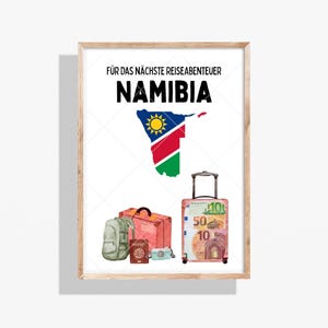 Könnte beinhalten: Gerahmter Druck mit dem Wort "NAMIBIA" in fetten schwarzen Buchstaben. Die Flagge Namibias wird als Kartenumriss dargestellt. Ein Koffer, ein Rucksack, ein Reisepass, eine Kamera und ein zweiter Koffer befinden sich unten.