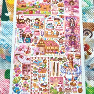 May include: A sticker sheet featuring colorful illustrations of desserts, cakes, and cute characters. The sheet includes images of ice cream, cupcakes, and other sweets, with Japanese text. The overall theme is a whimsical, kawaii aesthetic.