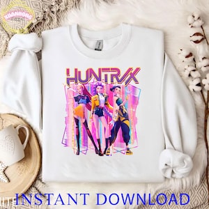 May include: White sweatshirt with the word "HUNTRX" in purple and three stylized figures in vibrant outfits. The figures are set against a geometric backdrop with pink, purple, and blue hues. The words "INSTANT DOWNLOAD" are at the bottom.