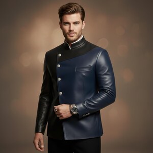 May include: A two-tone leather jacket in black and navy blue. The jacket features a mandarin collar, silver buttons, and a tailored fit. The model is wearing a white shirt underneath.