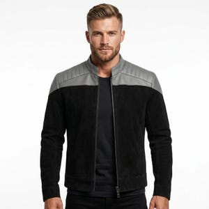 Peut inclure: Veste en daim noire avec empiècement et épaules en cuir gris. La veste a un col montant et une fermeture éclair sur toute la longueur. La veste est portée sur un t-shirt noir.