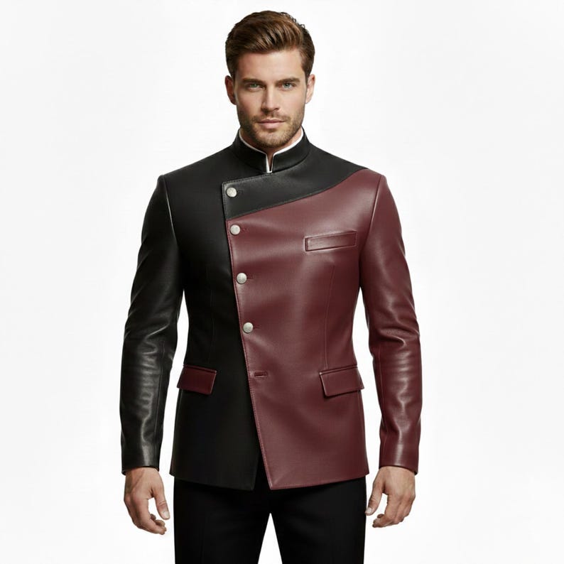 May include: A two-tone leather jacket in black and burgundy. The jacket features a mandarin collar, asymmetrical design, and silver buttons. The jacket has a tailored fit and a pocket on the burgundy side.