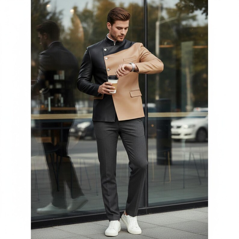 May include: A two-tone suit jacket in black and tan with a mandarin collar and a single-button closure. The jacket is paired with gray trousers and white sneakers. The person is holding a coffee cup and looking at their watch.
