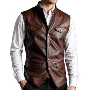 May include: A brown leather vest with a mandarin collar and four gold-colored buttons. The vest has two front pockets and is worn over a white dress shirt. The vest appears to be made of high-quality leather.