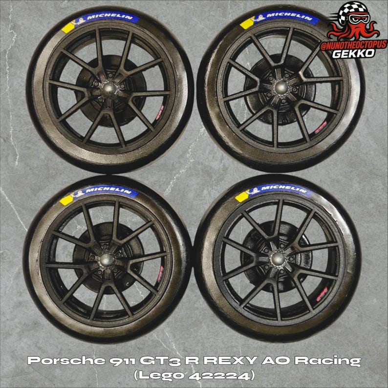 May include: Four black and gray car wheels with Michelin tires. Each tire has a blue and yellow Michelin logo. The wheels are from a Porsche 911 GT3 R REXY AO Racing Lego set.