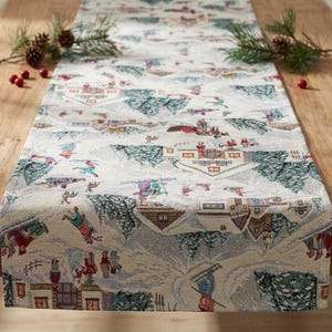 Puede incluir: Camino de mesa decorativo con un diseño de escena invernal. El camino de mesa presenta un fondo crema con un patrón repetido de esquiadores, casas cubiertas de nieve y árboles de hoja perenne. Piñas y bayas rojas están colocadas sobre la mesa de madera.