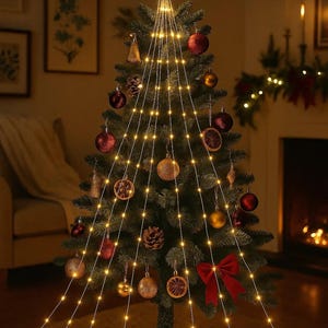Puede incluir: Un árbol de Navidad decorado con luces blancas cálidas, adornos y una estrella en la parte superior. El árbol está adornado con bolas rojas y doradas, piñas y un lazo rojo. Dos regalos envueltos con cintas rojas se encuentran en la base.