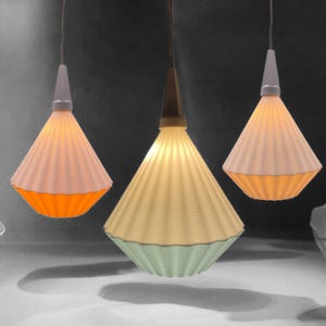 May include: Three cone-shaped pendant lights with ribbed lampshades. The lampshades are white, orange, and light green. The lights hang from the ceiling by thin cords, creating a modern lighting arrangement.