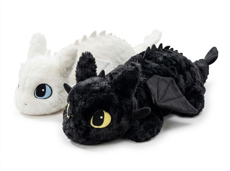 May include: Two plush dragon toys, one white and one black, are displayed side-by-side. The white dragon has blue eyes, while the black dragon has yellow eyes. Both have soft, textured fur, wings, and small horns.