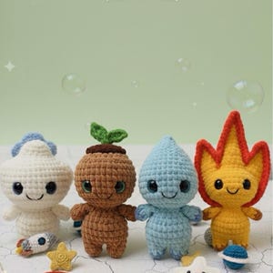 May include: A collection of four crocheted amigurumi figures representing the elements: air, earth, water, and fire. Each figure is a different color and has a unique design. Additional crocheted accessories include a rainbow, stars, and a rocket.