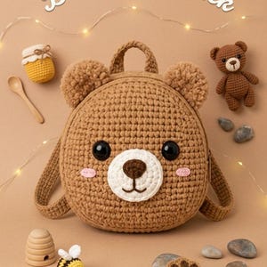 May include: A brown crochet bear backpack with black eyes, a white snout, and pink cheeks. The backpack has a handle and straps. The image also includes a small crochet bear, a honey pot, a wooden spoon, and a bee.