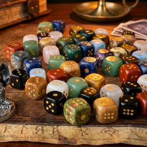 May include: A collection of colorful, gemstone dice in various colors including red, green, blue, and brown. Each die has gold-colored dots. The dice are arranged on a wooden surface with a map design, suggesting a tabletop game.