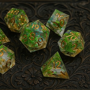 May include: Set of seven polyhedral dice with a forest-like design. The dice are clear with green and gold inclusions, and gold numbering. The dice are arranged on a dark, textured surface.