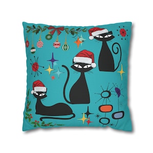 May include: A square throw pillow with a teal background featuring three black cats wearing red and white Santa hats. The design includes hanging Christmas ornaments, holly sprigs, and colorful starburst shapes scattered across the fabric surface.