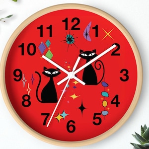 May include: A white ceramic mug with a black handle and the text "But First, Coffee" in a bold, black font. The mug is set against a blurred background, suggesting a cozy setting.