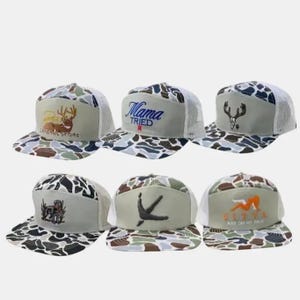 May include: Six camouflage trucker hats with various designs. One hat has a deer graphic and "GENERAL STORE" text. Another says "Mama Tried". Other hats feature a deer skull, a dog, a bird, and a graphic with text "SITTA ASS ON MY FACE".