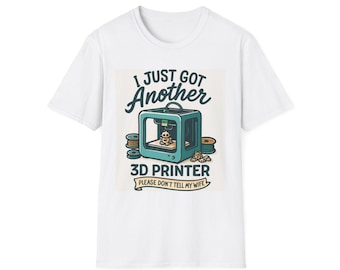 May include: White t-shirt with a graphic of a 3D printer and the text "I JUST GOT Another 3D PRINTER PLEASE DON'T TELL MY WIFE". The design includes spools of filament in a cartoon style.