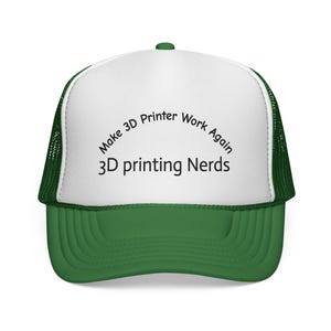 May include: A green and white trucker hat with the text "Make 3D Printer Work Again" and "3D printing Nerds" in black. The hat has a green brim and mesh back, and a white front panel.
