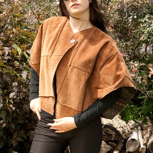 Puede incluir: Una chaqueta de ante marrón con un diseño único y cierre de botón. La chaqueta tiene manga larga y un ajuste holgado.
