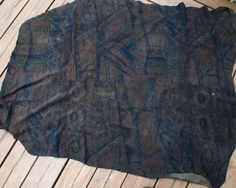 May include: A dark brown fabric with a geometric pattern in shades of blue, green, and brown. The fabric has a textured surface and a slightly faded appearance.