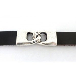 May include: A silver-toned metal clasp with a double loop design, attached to a black leather strap.