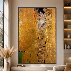 May include: A rectangular wall art print featuring Gustav Klimt's Portrait of Adele Bloch-Bauer I. The painting depicts a person in a gold dress with geometric patterns against a shimmering gold background with intricate mosaic-like details.