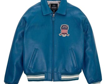 May include: A blue leather jacket with a collared neckline and a zipper closure. The jacket features a patch with red, white, and blue details. The cuffs and hem have white and green stripes. The brand name "AVIREX" is visible.