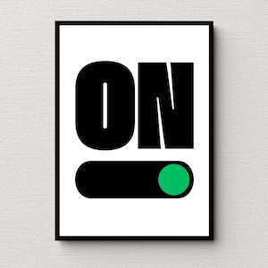 May include: A framed art print with the word "ON" in bold, black letters. Below the text is a black horizontal rectangle with a green circle on the right side, resembling a power button. The background is white.