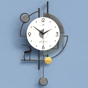 May include: A modern wall clock with a white face, black hands, and a minimalist design. The clock features a black metal frame with geometric shapes, a deer silhouette, and a yellow and gray accents. The clock is mounted on a blue wall.
