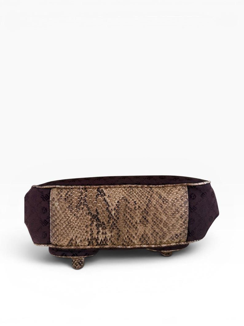 May include: A rectangular handbag with a snakeskin pattern on the front and sides. The bag has a dark purple fabric on the top and ends, with small feet. The bag is a neutral colour.