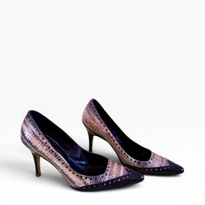 May include: A pair of high-heeled pumps with a snakeskin pattern in shades of pink, brown, and black. The shoes have pointed toes, a dark trim, and a stiletto heel. The heels are approximately 3 inches (7.6 cm) high.