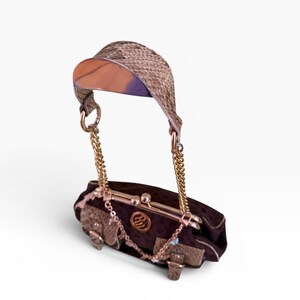 May include: A dark brown handbag with a gold chain strap and a woven visor-like handle. The bag features gold hardware and decorative accents. The bag is approximately 20 cm long.