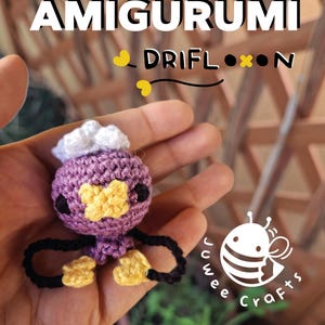 Può includere: Una bambola all'uncinetto amigurumi Drifloon in miniatura fatta a mano in viola, giallo, nero e bianco. La bambola ha una testa rotonda, un viso giallo e braccia e gambe nere. L'immagine include il testo "Mini Amigurumi Drifloon" e "PDF Crochet Pattern".
