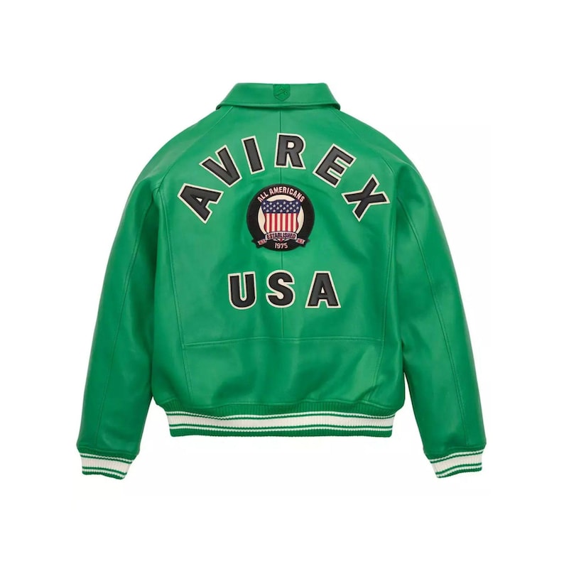 Pu&ograve; includere: Giacca in pelle verde con polsini e colletto a righe bianche e verdi. La parte posteriore presenta la scritta "AVIREX" sopra una toppa circolare e la scritta "USA".