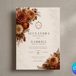 May include: A wedding invitation card featuring a cream-colored background with embossed white floral borders. The design includes clusters of rust-colored roses and dahlias, a central monogram with the letters A and G, and black printed text.