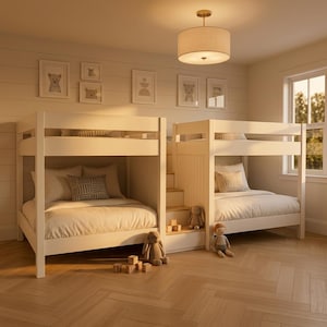 May include: Two white bunk beds connected by a central staircase. Each bed features white bedding, patterned throw pillows, and a wooden frame. Stuffed animal toys are placed on the floor and stairs. A drum-style ceiling light hangs above.