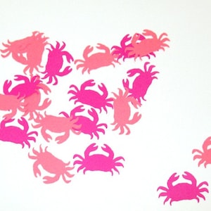 May include: Pink and light pink paper cutouts of crabs scattered on a white background.