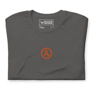 Könnte beinhalten: Ein dunkelgraues T-Shirt mit einem kleinen orangefarbenen Lambda-Symbol in der Mitte der Brust. Das innere Nackenetikett zeigt den Text Mutation Design, Größe S und Made in Nicaragua. Das Shirt hat einen Rundhalsausschnitt und kurze Ärmel.