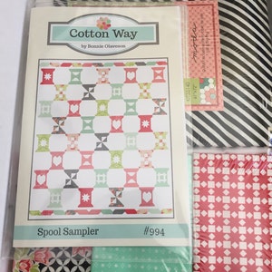 May include: A quilting kit containing fabric and a pattern. The pattern is titled "Spool Sampler" by Bonnie Olaveson. The kit includes various fabrics with floral, geometric, and striped patterns. The kit dimensions are 155cm x 183cm.