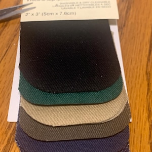 May include: A package of eight twill iron-on patches in various colors, including black, green, tan, and navy blue. Each patch measures 2 inches by 3 inches (5cm x 7.6cm). The package includes text in English and French.