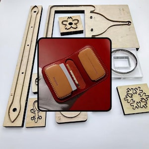 May include: A selection of wooden leathercraft tools and a red leather wallet. The tools feature diverse shapes and sizes, including a flower, a snowflake, and a lizard. The wallet is brown and has the word "Mospoke" on it.