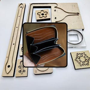 Könnte beinhalten: Ein offenes braun-schwarzes Lederportemonnaie mit goldenem Reißverschluss, umgeben von verschiedenen Holzwerkzeugen und Stanzformen. Die Werkzeuge umfassen Formen wie eine Blume, einen Schneeflocke und eine Eidechse, was auf Lederhandwerk hindeutet.