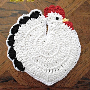 May include: White crocheted chicken dishcloth with black and red accents. The dishcloth is shaped like a chicken with a red comb and wattle, black eyes, and a yellow beak. The text "Sunnydale Farm" is written above the chicken and "Theresas This-n-That" is written below the chicken.