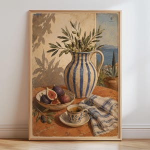 May include: A framed art print depicting a still life scene on a terracotta surface. A blue and white striped pitcher holds olive branches. Nearby, a bowl contains fresh figs, a cup and saucer sit beside a blue and white striped cloth.