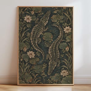 May include: A rectangular wall art print in a light wood frame featuring a dark, moody illustration of two alligators swimming in a pond. The scene is filled with green lily pads, tall aquatic grasses, and pale white lotus flowers in bloom.