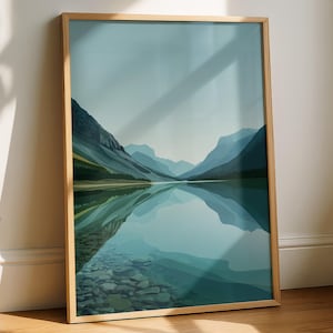 Può includere: Una stampa artistica incorniciata raffigurante un sereno paesaggio di montagne riflesse in un lago calmo. L'opera d'arte utilizza sfumature di blu e verde per rappresentare lo scenario naturale. La cornice è in legno chiaro, aggiungendo un tocco naturale all'opera.
