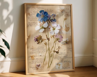May include: A framed botanical print featuring pressed flowers in shades of blue, white, and purple. The flowers are arranged on a vintage paper background with handwritten script. The frame is made of light-colored wood.