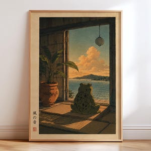 以下が含まれることがあります： 海を見下ろすカエルを描いた額入りのアートプリント。カエルは緑色で濃い斑点があり、マットの上に座っています。左側には鉢植えの植物があります。プリントには日本語のテキストと暖色系の色合いが使用されています。