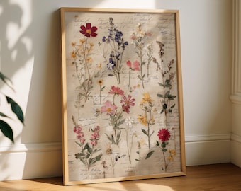 May include: A framed botanical print featuring an assortment of pressed flowers in various colors, including red, yellow, pink, and purple. The flowers are arranged on a vintage-style background with handwritten script. The frame is made of light-colored wood.