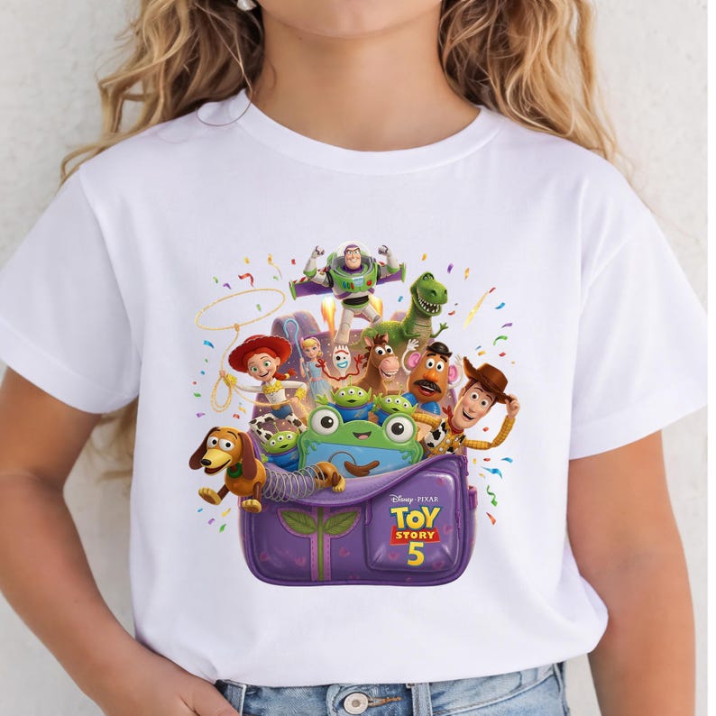 May include: A white short-sleeved t-shirt featuring a colorful graphic of Toy Story characters emerging from a purple backpack. The print includes Buzz Lightyear, Woody, Jessie, Rex, Slinky Dog, Mr. Potato Head, and the text Disney Pixar Toy Story 5.